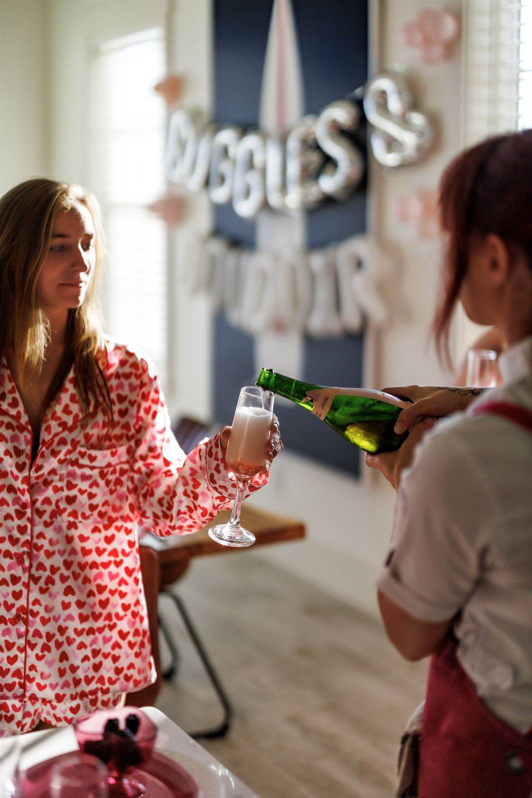 Chef pouring champagne for a guest in heart-print pajamas
