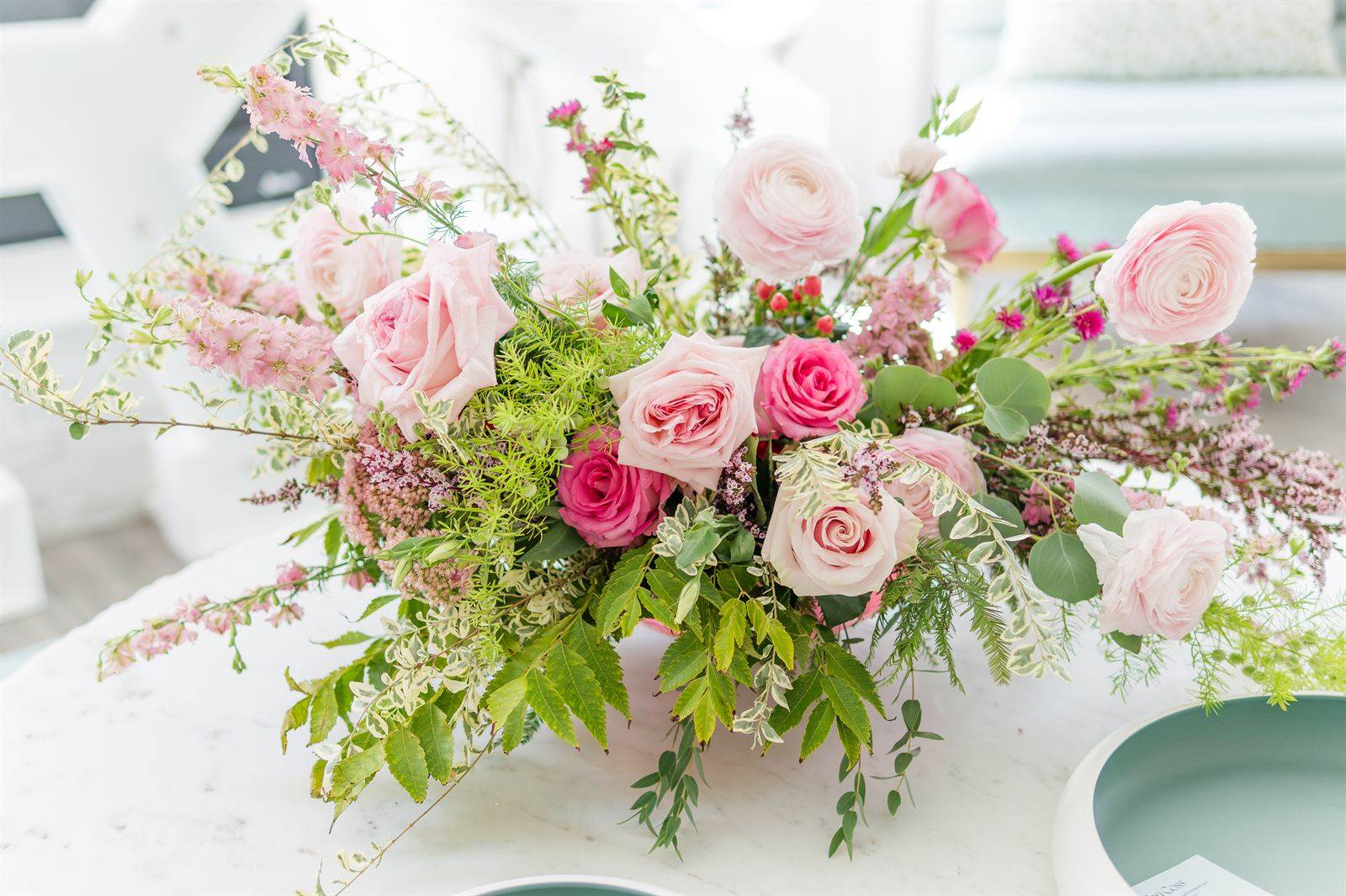 Pink rose and greenery centerpiece on a white table