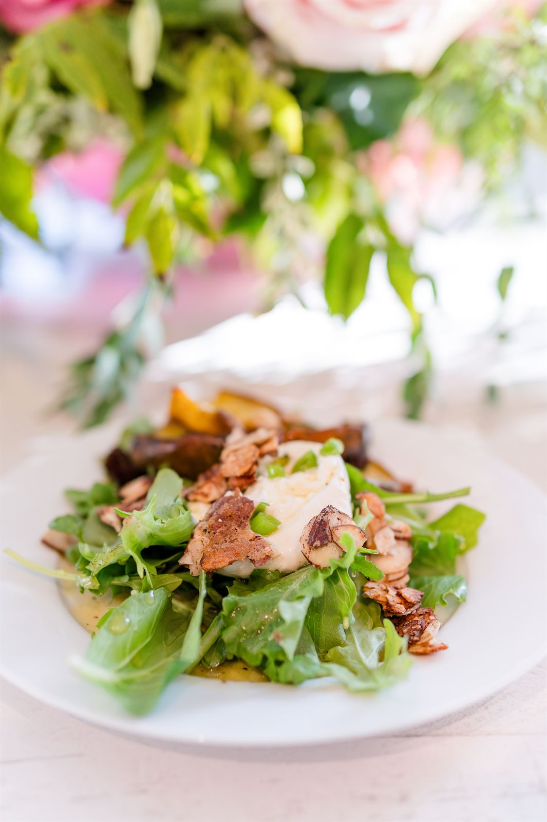 Plated salad with seared fish served under a floral centerpiece