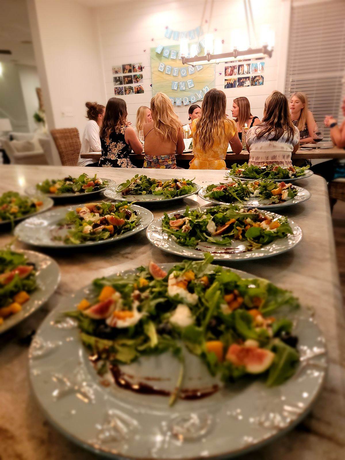 Plated fig and arugula salads lined up on a kitchen island