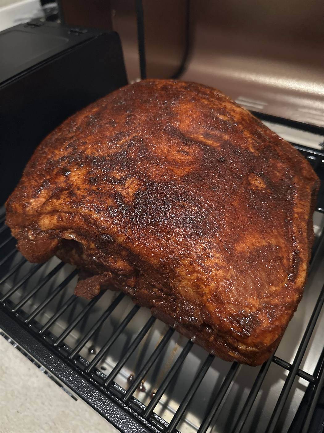 Smoked pork shoulder with a dark bark, ready to pull