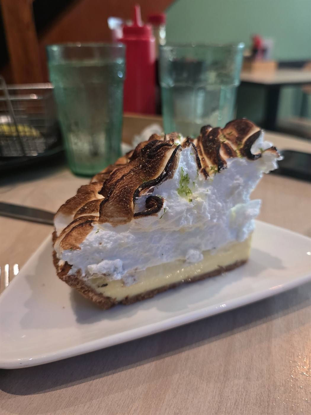 A slice of key lime pie with a tall toasted meringue