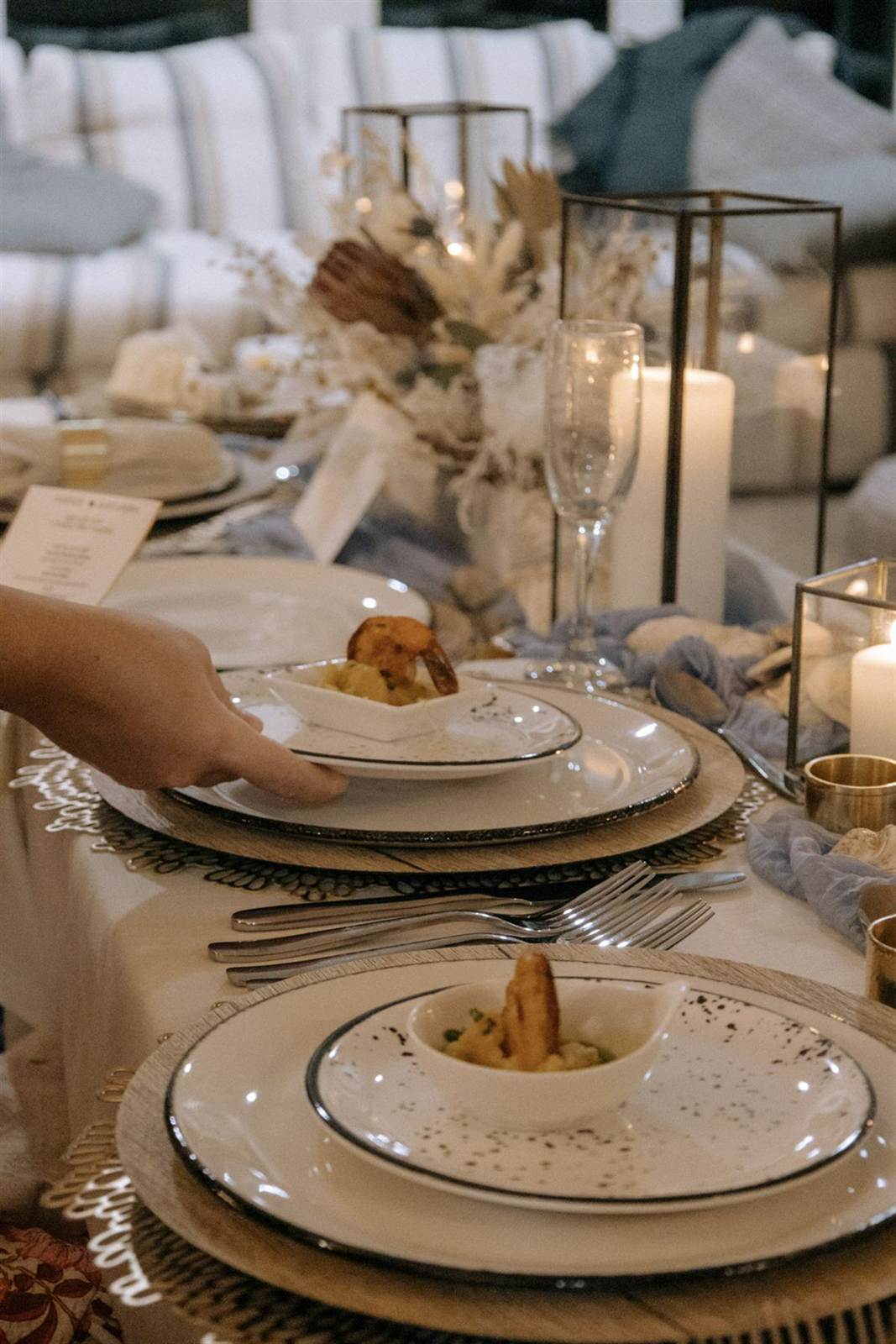 Candlelit dinner table as a server sets down the first course
